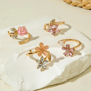 Set de anillos florales dorados con rosas rosas, perlas y cristales sobre piedra blanca
