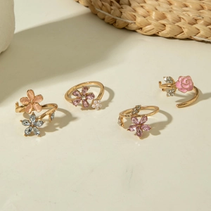 Detalle de cuatro anillos florales dorados con cristales de colores y perlas finas