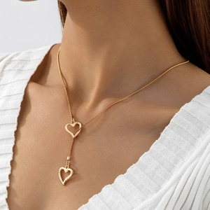 Gros plan du collier doré à double pendentif en forme de cœur porté par un mannequin