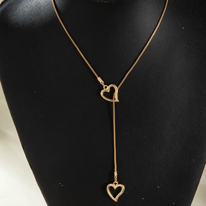 Détail macro d'un collier lasso doré en Y avec deux pendentifs en forme de cœur