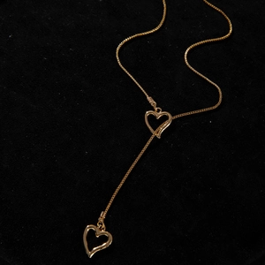 Détail macro du collier en Y doré avec pendentif cœur et chaîne box sur velours noir