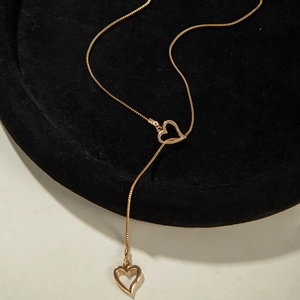 Gros plan du collier doré en Y avec deux cœurs sur un support en velours noir