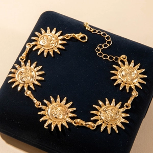 Vintage gold sunflower anklet with embossed sun faces on a luxury velvet display