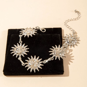 Detailed view of vintage silver sunflower anklet with engraved faces on black velvet