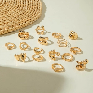 Set of 15 gold rings including heart shapes and geometric bands on a neutral background