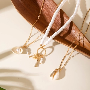 Colliers bohèmes superposés avec coquillages, perles et pendentif palmier sur feuilles