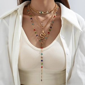 Close-up of layered gold snake necklaces featuring crystal accents on a female model