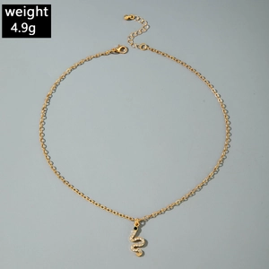 Detailed view of a gold snake pendant necklace featuring white crystals and a green gem eye