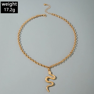 Macro detail of gold snake pendant with etched scales and layered Y-chain design