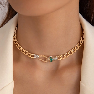 Detail of gold snake head pendant with olive green gemstones and sparkling crystals