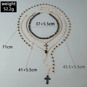 Detail showing cross pendant and heart charms on multilayered gold chain necklace set