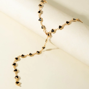 Detail of gold chain necklace featuring multiple black heart charms on a sleek cylinder