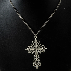 Macro shot of silver gothic hollow cross pendant with retro textured metal engraving