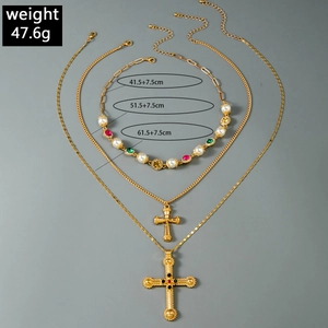 Detailed view of triple-layered gothic cross pendant necklaces with pearls and colorful gems