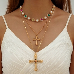 Close-up of layered necklace with vintage cross pendants and colorful gemstones