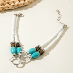 Detail of bohemian turquoise beaded bracelet with intertwined silver heart charms and lobster clasp