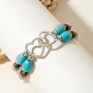 Detail of bohemian turquoise beaded bracelet with intertwined silver metal hearts