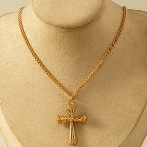 Detailed view of a vintage gold cross pendant necklace with gothic architectural carvings