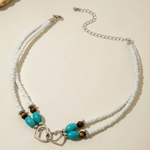Detail of bohemian layered beaded necklace featuring interlocking silver metal hearts