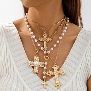 Detail shot of multi-layered gold cross necklaces with pearls on a female model neck