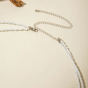 Detail of double-layer white beaded necklace with silver lobster clasp and extension chain