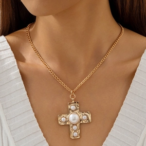 Detail shot of vintage hollow cross pendant with pearls on a gold curb chain necklace