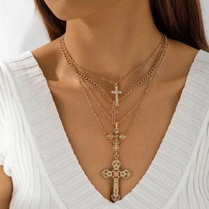 Detailed view of layered gold cross necklaces with vintage carved pendants on model