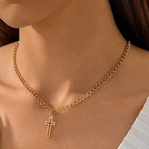 Close-up of a layered gold cross pendant necklace with a minimalist hollow gothic design