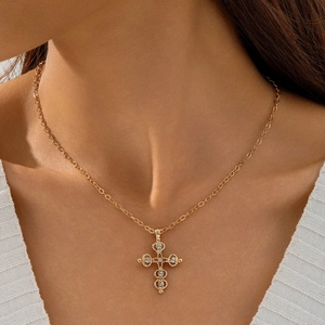 Close-up of a gold vintage cross pendant necklace with white zircons on a model