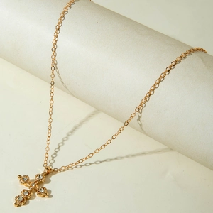 Detailed macro view of a vintage gold cross pendant necklace with zircon inlay