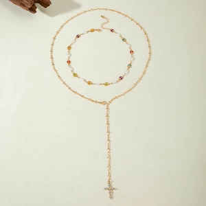 Détail du collier en Y doré avec pendentif croix et perles avec papillons colorés