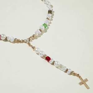 Détail du collier de perles avec perles colorées et un pendentif croix dorée