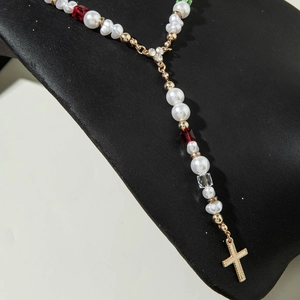 Vue détaillée du collier chapelet avec perles blanches, cristaux rouges et croix