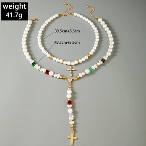 Détail de colliers de perles superposés avec pendentifs croix et perles de verre