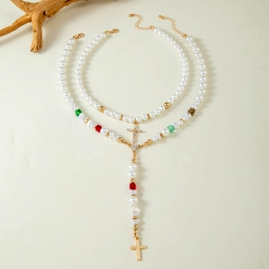 Détail de colliers en perles superposés avec croix dorées et perles de couleur