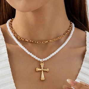 Ensemble collier multicouche chaîne dorée et perles avec croix porté par un mannequin