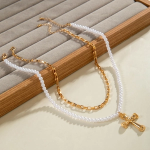 Détail du collier double rang en maille dorée et perles avec pendentif croix texturé