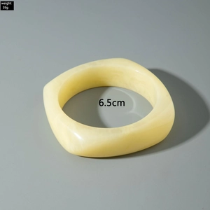 Detail of 6.5cm cream acrylic bangle featuring thick square design and marbled texture