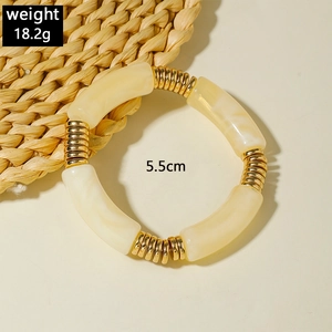 Detail of beaded stretch bracelet with marble acrylic tubes and gold metal rings