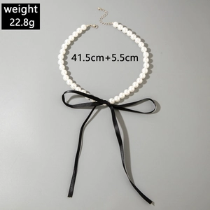 Macro view of French pearl necklace featuring black satin bow and adjustable silver clasp
