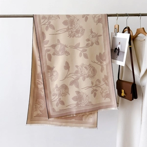 Detail of floral beige scarf with houndstooth borders and fringe on a metal hanger