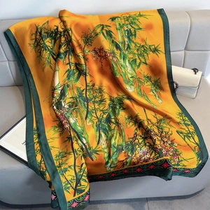 Elegant orange silk-like square scarf with bamboo print draped over a luxury sofa