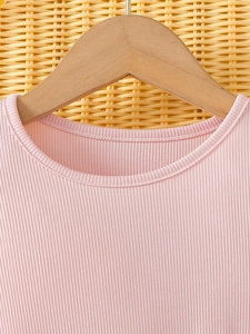 Pink rib-knit dress for girls with classic round neck on a wooden hanger