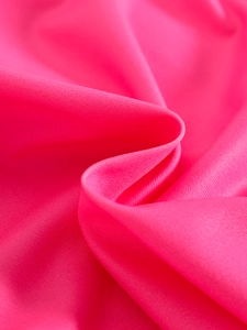 Close-up of bright pink smooth knit fabric with silky texture and soft drape detail