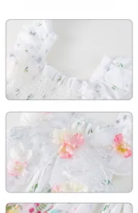 Detail of white girls dress showing delicate 3D floral embroidery and pearl beads