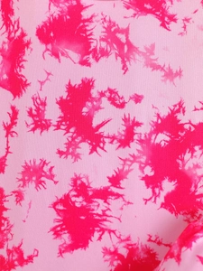 Close-up of pink tie-dye fabric texture showing vibrant ink splash patterns for kids' sets