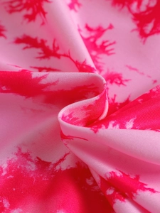 Close-up of soft tie-dye fabric texture in deep red and pink for kids sportswear