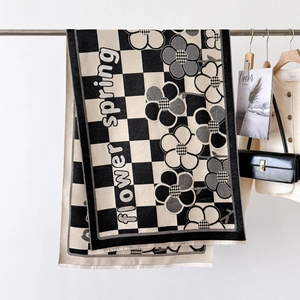 Detail of floral and checkerboard patterned scarf with delicate fringes on a hanger