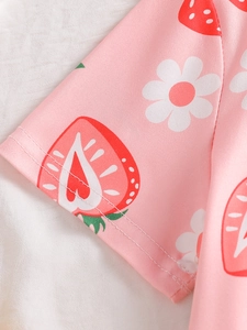 Close-up of strawberry and daisy prints on soft pink cotton fabric with neat stitching
