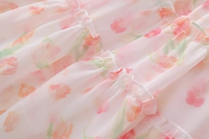 Detailansicht der gestuften Rüschen und des rosa Tulpenmusters auf dem Chiffonkleid